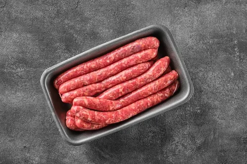 A pile of cooked sausages on a cutting board.
